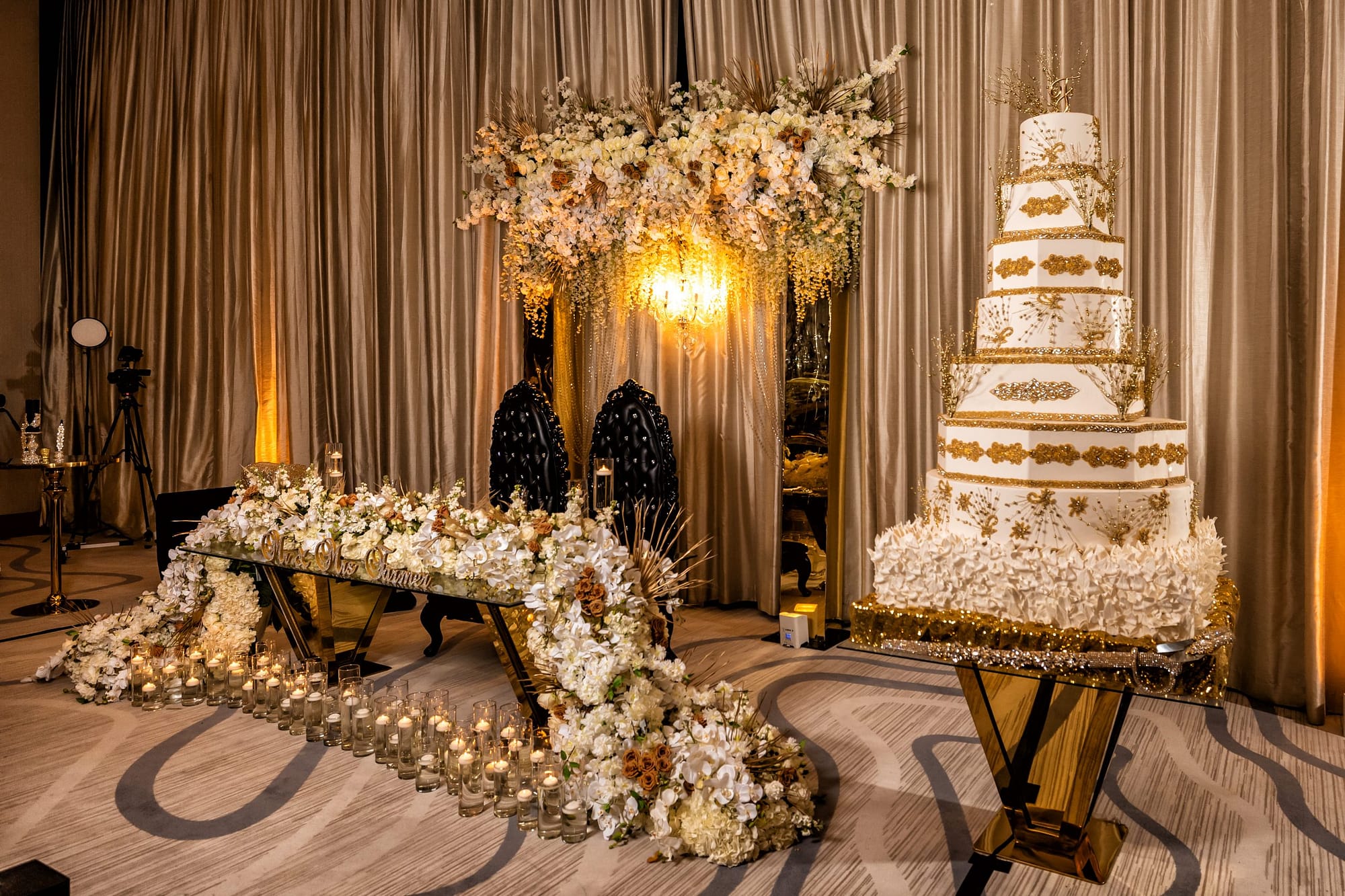 Gold and Black Exgtravegant Sweetheart Table with Six Tier Cake with Gold Detailing and White Florals