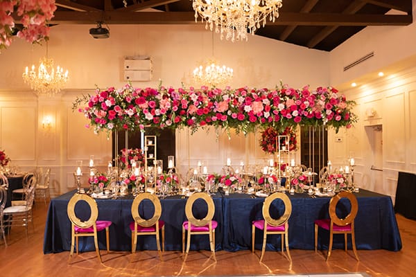 Ballroom Reception with Gold and Pink Chairs and a Navy Linen and Pink and Red Florals
