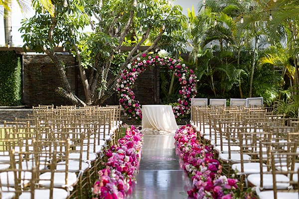 Gold Chivari Chairs with Pink and Red Rose Aisle Floral Details and Circle Greenery and Red and Pink Rose Arch Outdoor Wedding Ceremony