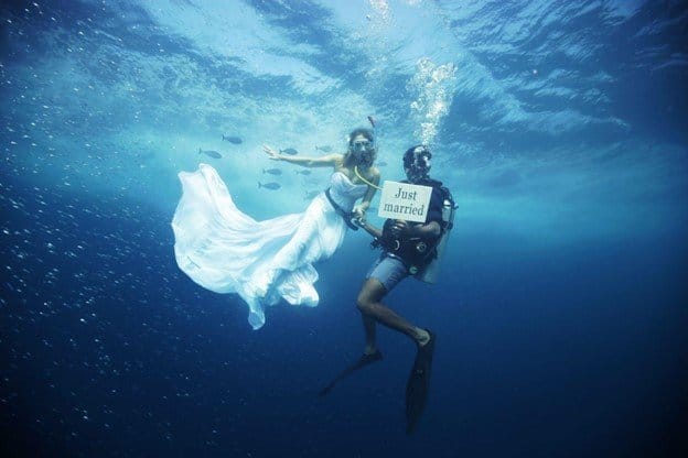 A married couple dive into the water in the Maldives. 
