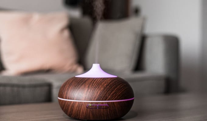 Contemporary smart humidifier on table emitting water vapor and moisturizing air in cozy room