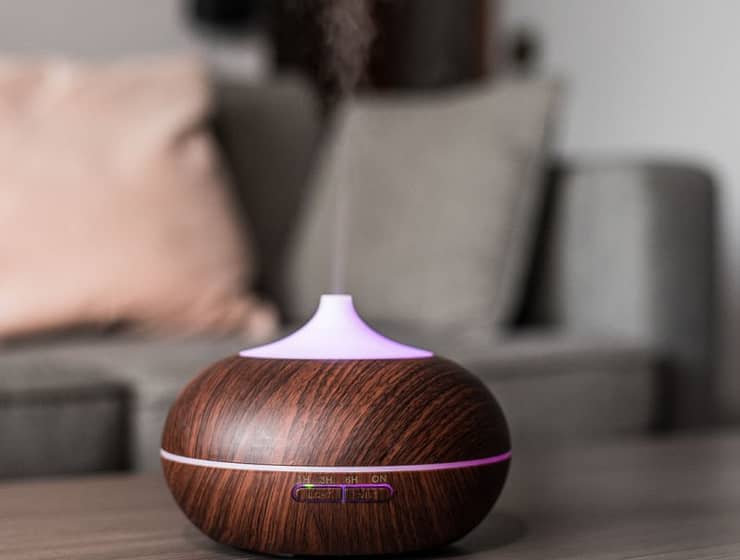 Contemporary smart humidifier on table emitting water vapor and moisturizing air in cozy room