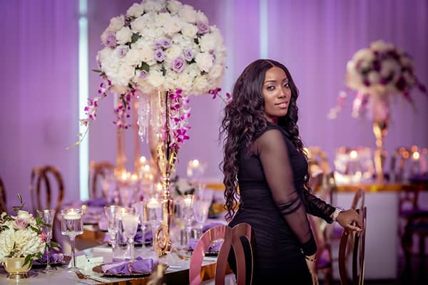 African American Florida Based Wedding Planner in Wedding Reception Ballroom with Tall White Floral Centerpieces with Purple Accents African American Florida Based Wedding Planner in Wedding Reception Ballroom with Tall White Floral Centerpieces with Purple Accents